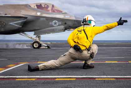Navy Lt. Cmdr. Jarrett Walden signals and F-35C Lightning II as it launches from the USS Abraham Lincoln in the South China Sea, Jan. 4, 2026. Photo credit Navy Seaman Sameul Evarts.